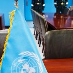 UN flag on the negotiation table in the JSA with North Korean soldiers in the background