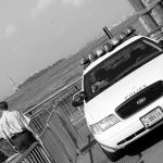 police car and officer watching the statue of liberty in Ellis island NYC USA black and white