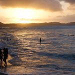 people in the sea at sunset at Baia dos Golfinhos in Brazil