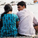 couple sitting on the Versova beach in Mumbai India in 2011 amongst trash