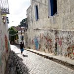 man walking in an empty street full of graffiti in Olinda in Brazil
