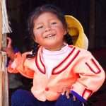 a smiling little girl with braids at Lake Titicaca in Peru