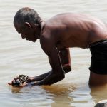 a local man is in the Narmada river picking up rocks from the bottom of the river at Marble Rocks central India
