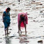 woman picking up her shoes on the Versova Mumbai beach full of plastic in 2011 before the clean up of history
