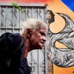 older woman walking in the street callejon de hamel by an art wall in la havana cuba