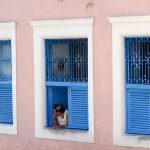 woman watching in the streets from a blue window in Olinda Brazil