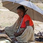 portrait of a local older woman protecting herself from the sun with an umbrella and staring at me in Marble Rocks India