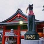 A statue of a fox holding a key in its mouth at the main gate of the Fushimi Inari shrine in Kyoto Japan